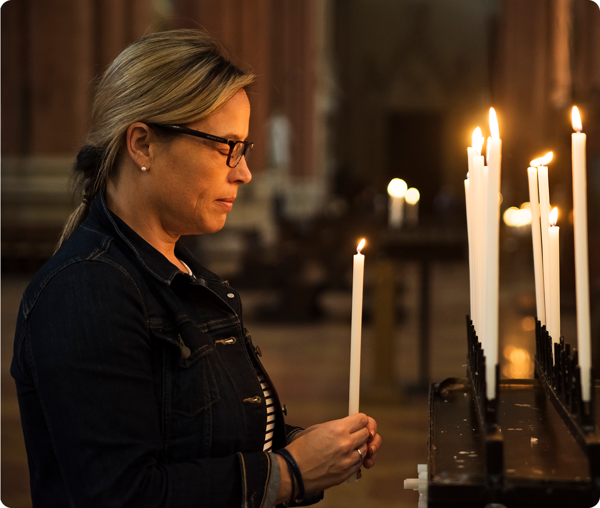 Woman lighting candle in a dimly lit church.