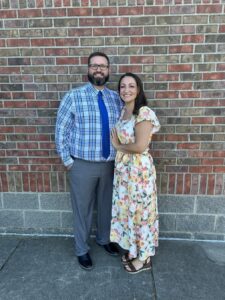 Smiling couple posing against a brick wall.